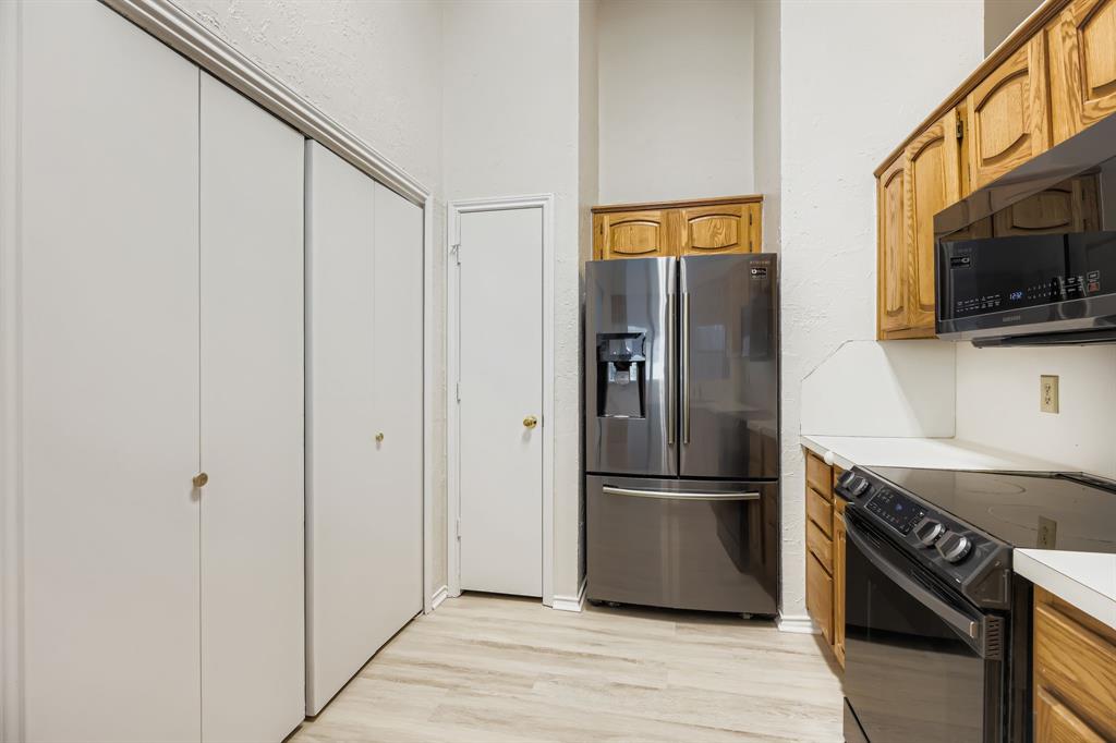4319 Harvest Hill Road Carrollton, TX 75010 - Photo 10 of 28 Kitchen with black / electric stove, stainless steel fridge, light countertops, light wood-style flooring, and brown cabinetry