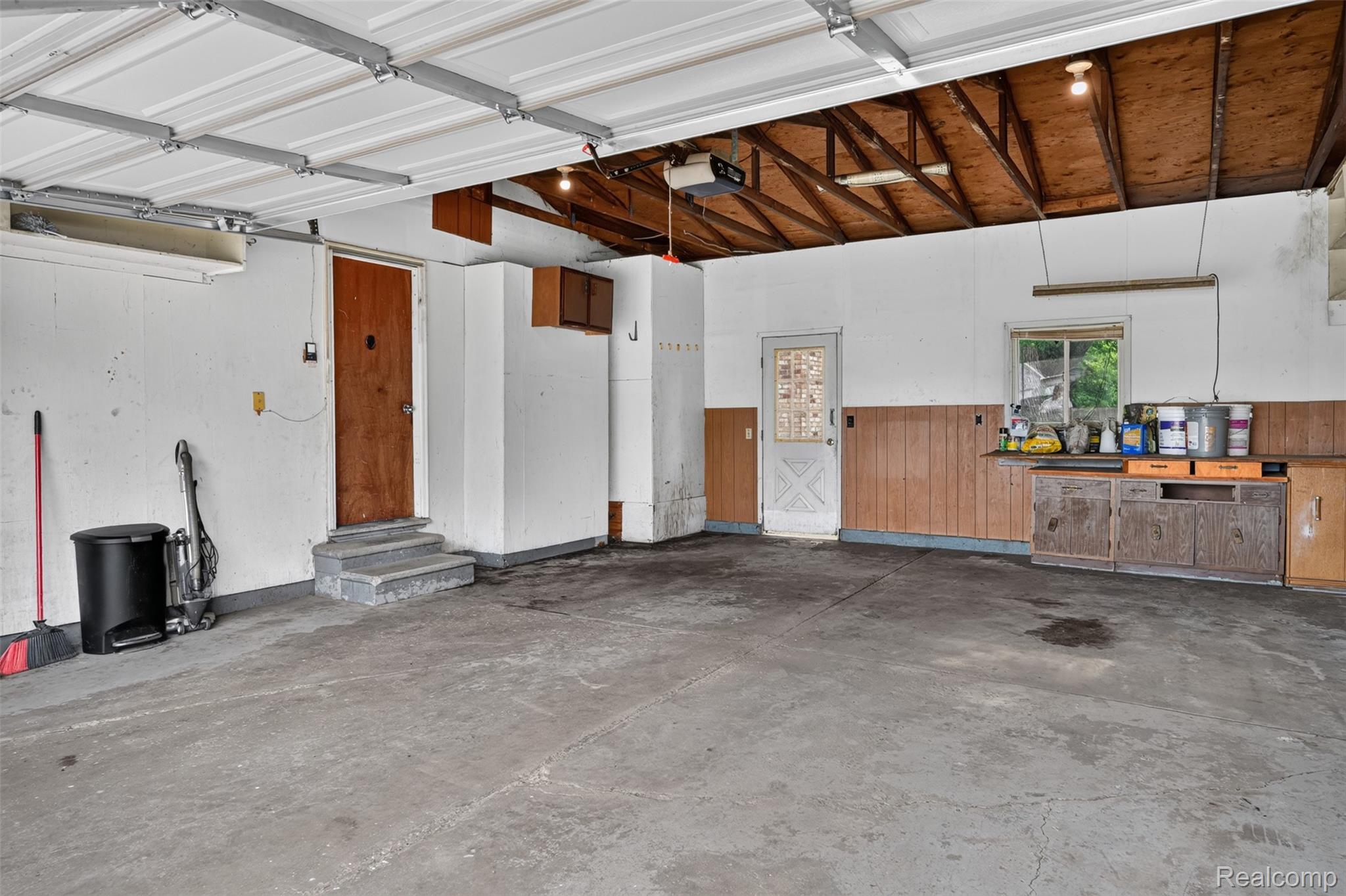 5457 Reid Road Swartz Creek, MI 48473 - Photo 40 of 51 Spacious two-car garage with concrete flooring, exposed ceiling joists, and a garage door opener