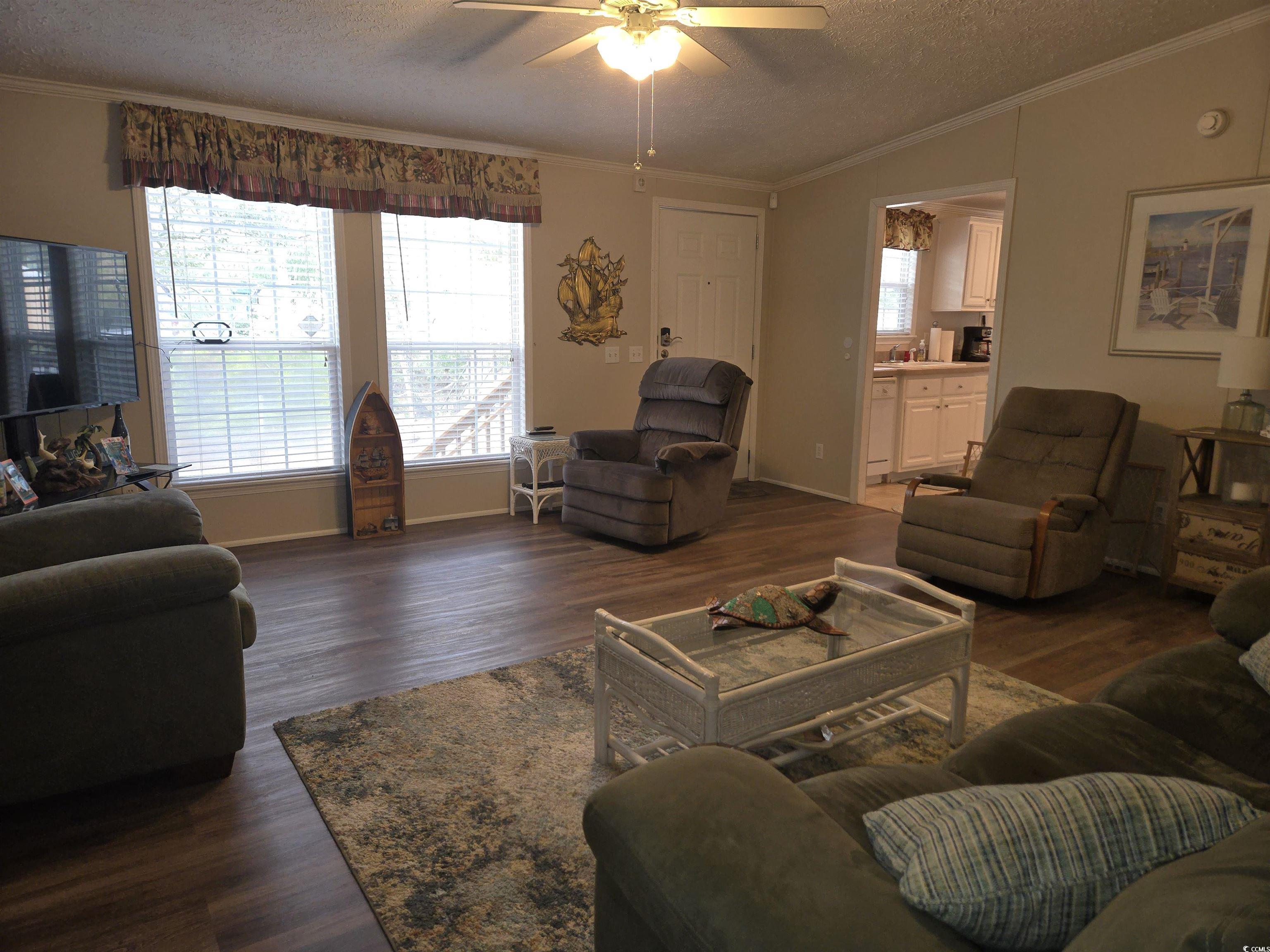 361 East Canal Street Murrells Inlet, SC 29576 - Photo 5 of 35 Living area featuring dark wood-style flooring, ceiling fan, crown molding, and vaulted ceiling