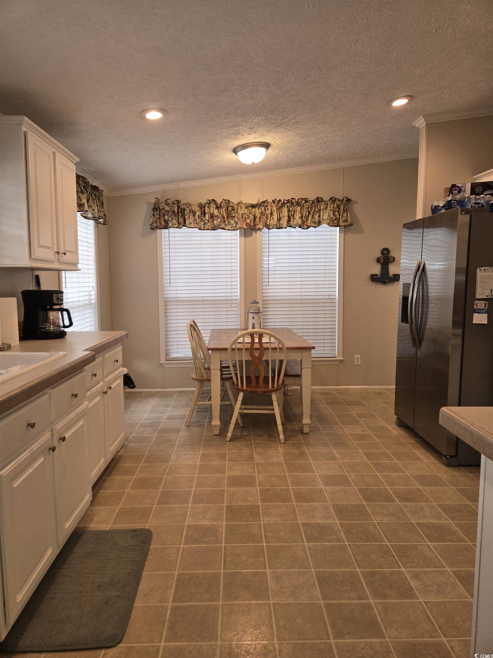 361 East Canal Street Murrells Inlet, SC 29576 - Photo 8 of 35 Kitchen featuring white cabinetry, tile patterned floors, stainless steel fridge with ice dispenser, and ornamental molding