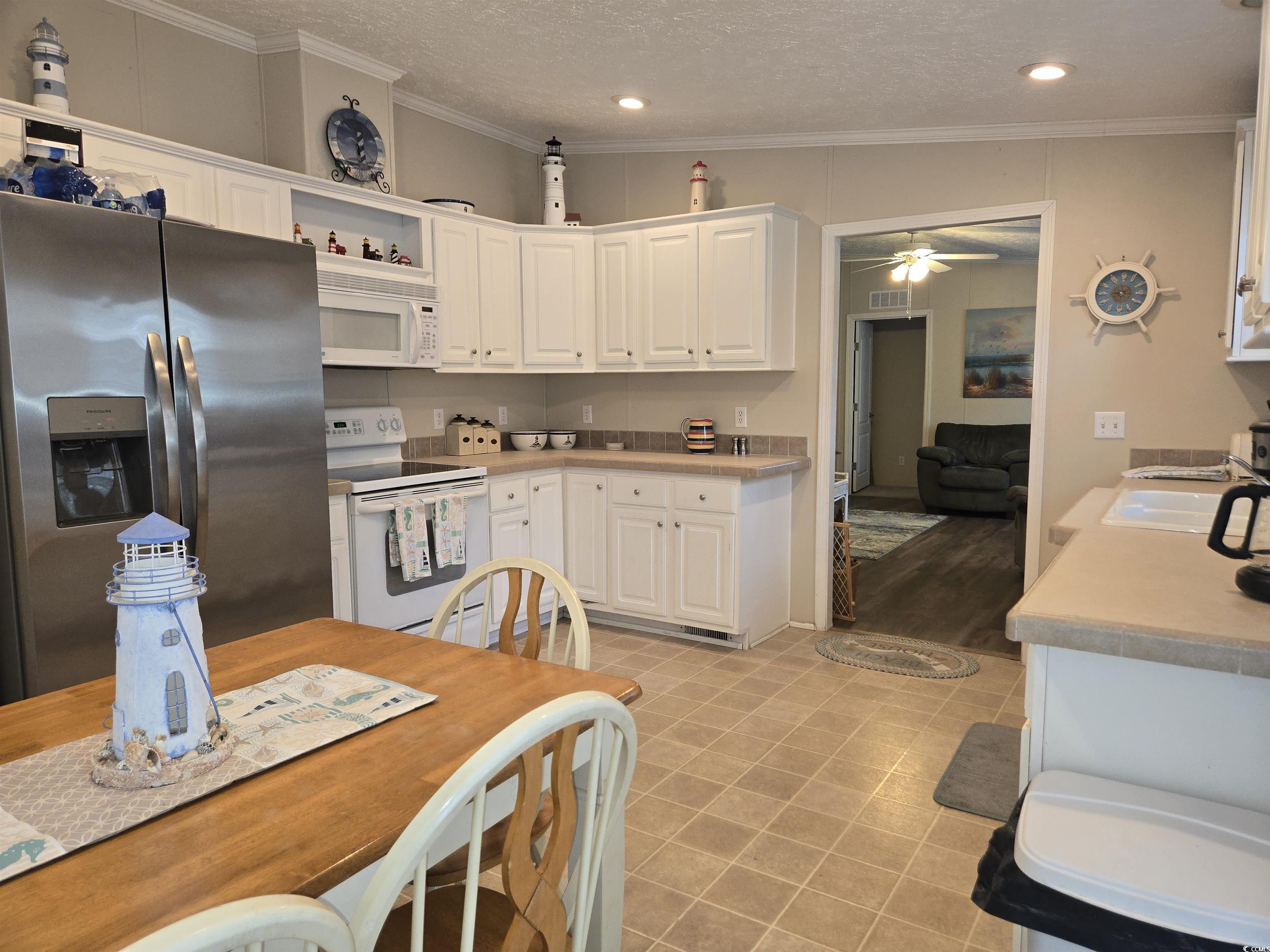 361 East Canal Street Murrells Inlet, SC 29576 - Photo 9 of 35 Kitchen featuring crown molding, ceiling fan, white cabinets, white appliances, and a sink