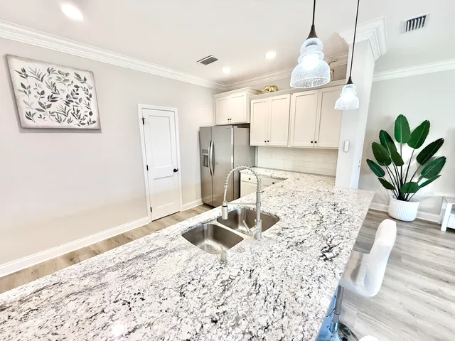 a kitchen with stainless steel appliances kitchen island granite countertop a sink a refrigerator and a granite counter tops