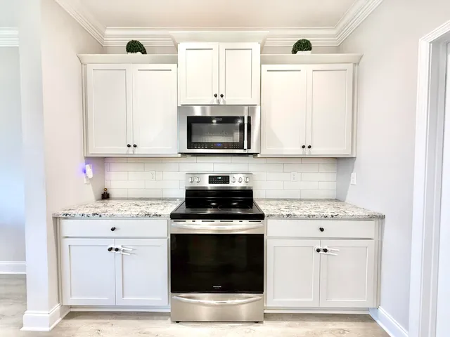a kitchen with stainless steel appliances granite countertop a stove a microwave and a white cabinets