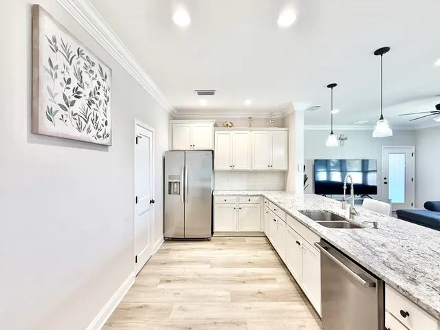 a kitchen with stainless steel appliances kitchen island granite countertop a refrigerator and a sink