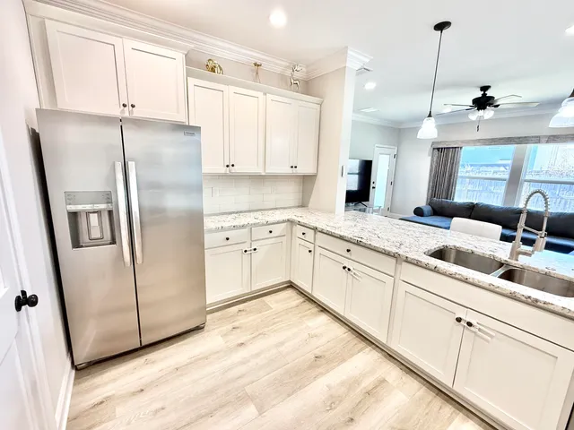 a kitchen with stainless steel appliances granite countertop a refrigerator sink and white cabinets