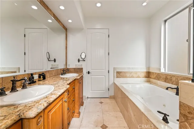 a bathroom with a granite countertop tub sink and mirror
