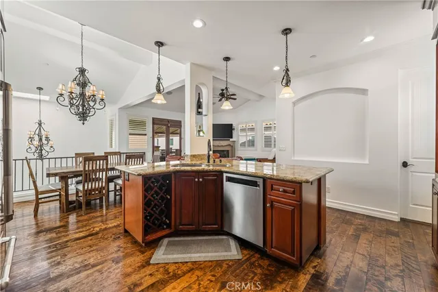 a kitchen with stainless steel appliances granite countertop a stove a sink dishwasher a dining table and chairs with wooden floor