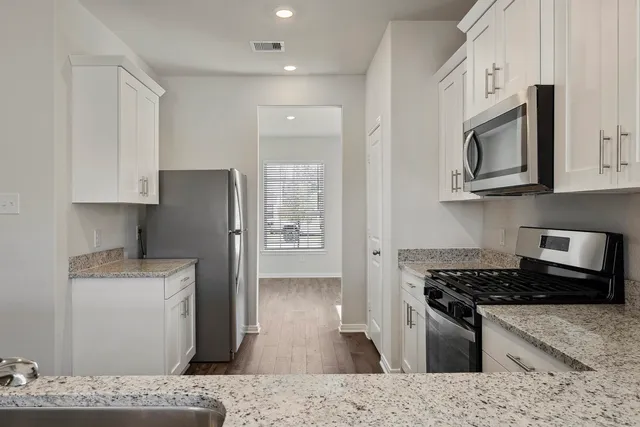 a kitchen with stainless steel appliances granite countertop a refrigerator stove top oven and sink