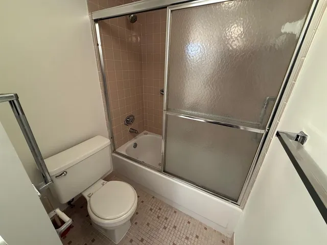 a white toilet sitting next to a shower