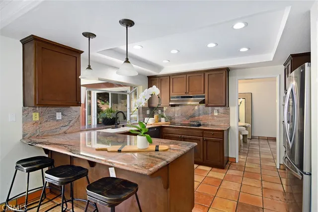 a kitchen with stainless steel appliances granite countertop a refrigerator a stove and a sink with cabinets