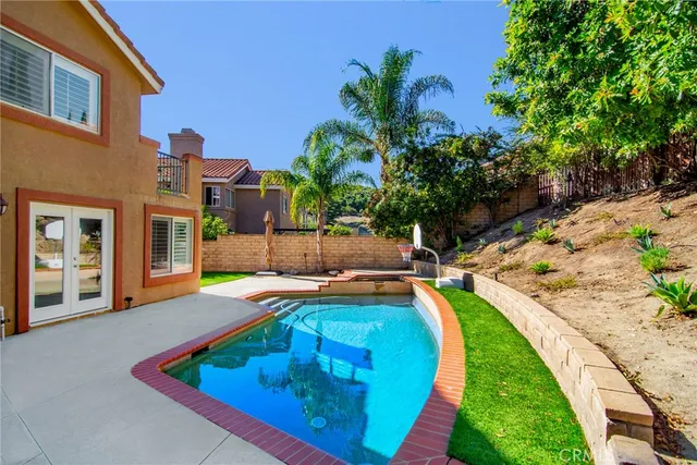 a view of swimming pool with lounge chair and palm trees