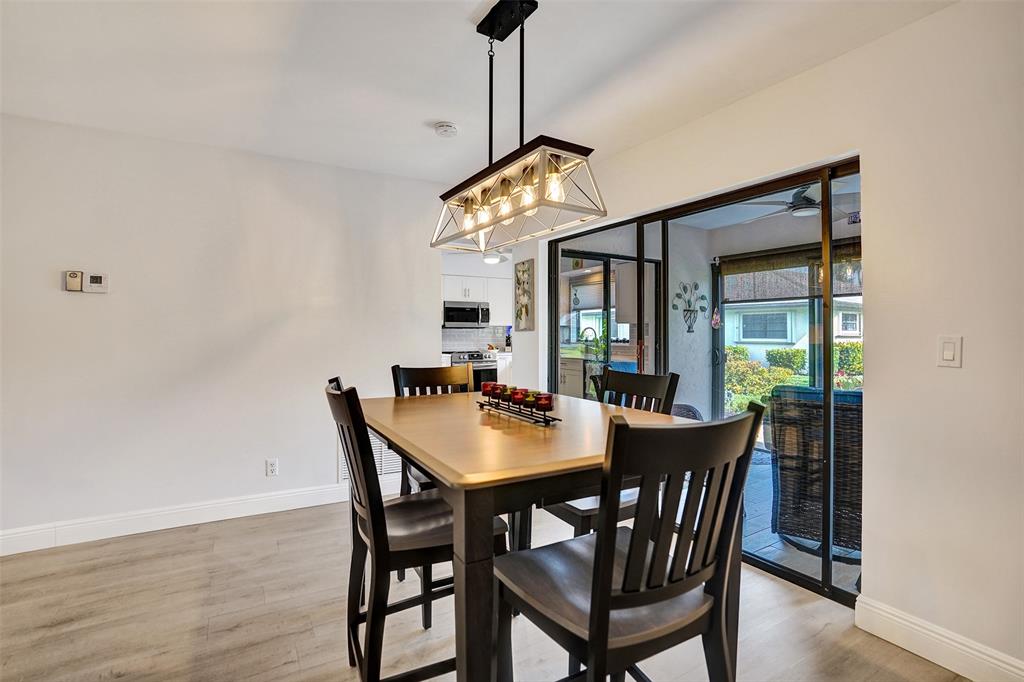 4840 Greentree Lane, Unit B Boynton Beach, FL 33436 - Photo 16 of 68 a dining room with furniture a chandelier and wooden floor