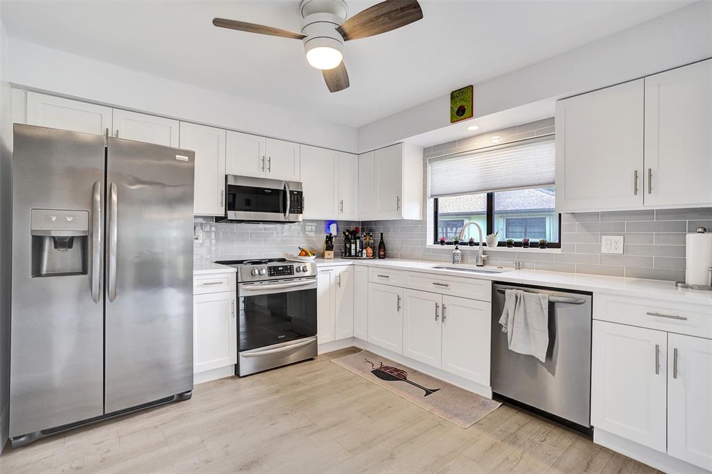 4840 Greentree Lane, Unit B Boynton Beach, FL 33436 - Photo 23 of 68 a kitchen with white cabinets stainless steel appliances and a window