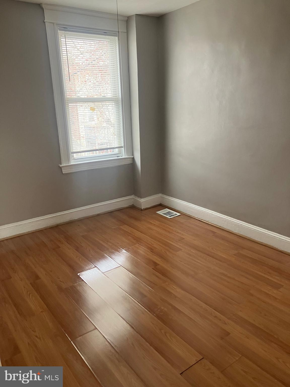 2540 Aisquith Street Baltimore, MD 21218 - Photo 8 of 15 an empty room with wooden floor and windows