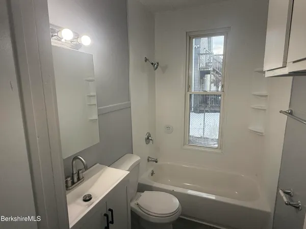 a bathroom with a granite countertop sink toilet a mirror and shower