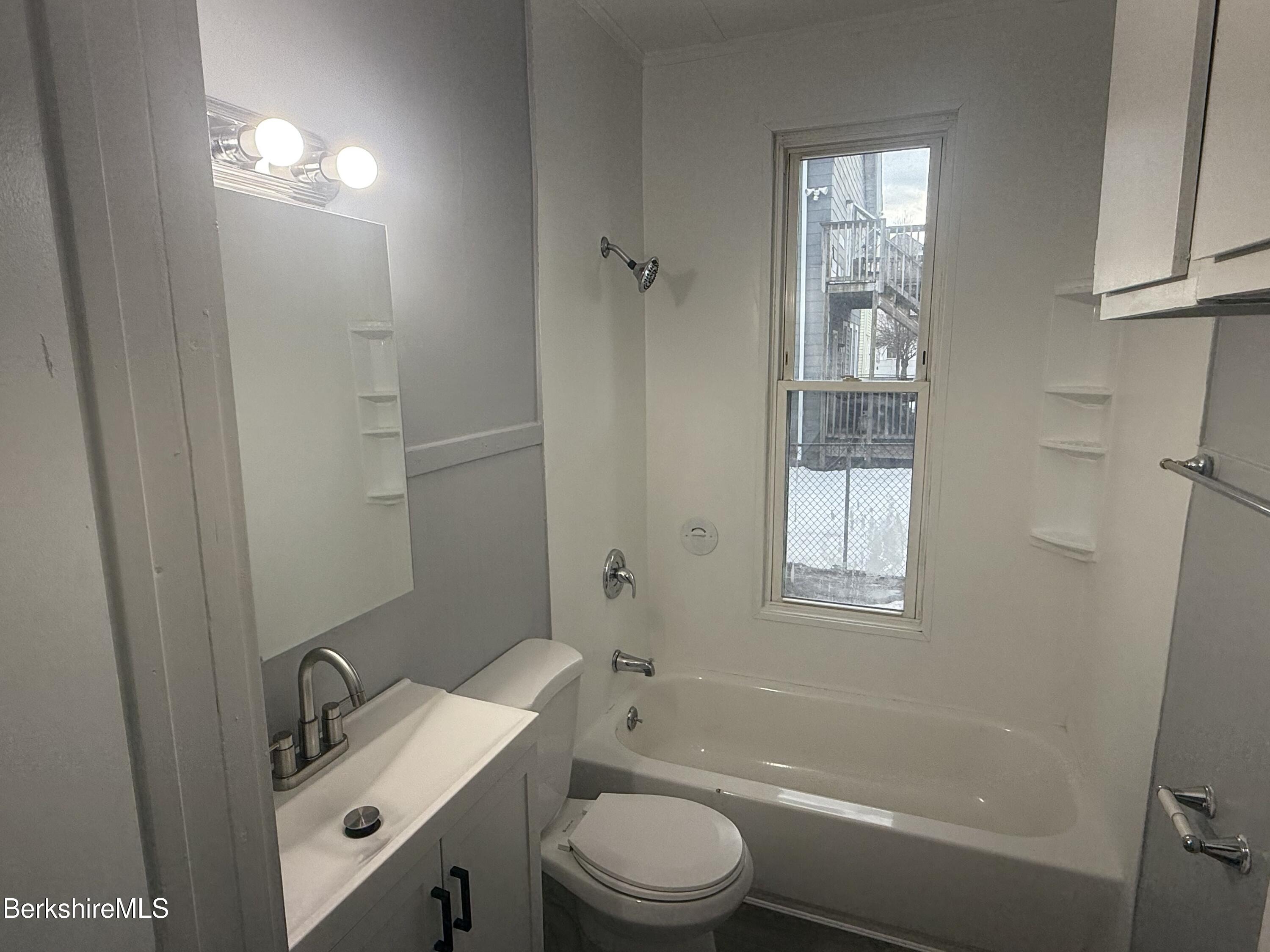 126 Appleton Avenue, Unit 1 Pittsfield, MA 01201 - Photo 6 of 8 a bathroom with a granite countertop sink toilet a mirror and shower