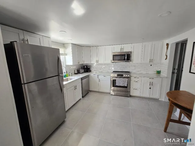 a kitchen with white cabinets and stainless steel appliances