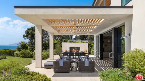 a view of a patio with table and chairs potted plants and floor to ceiling window