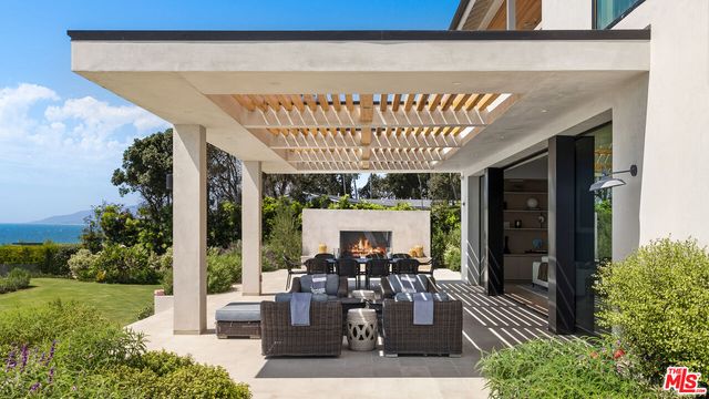 a view of a patio with table and chairs potted plants and floor to ceiling window