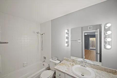 a bathroom with a granite countertop sink toilet and shower
