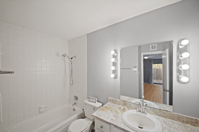 a bathroom with a granite countertop sink toilet and shower