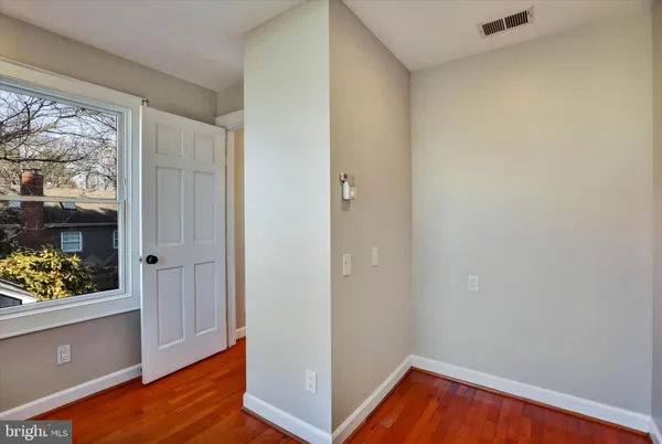 a view of an empty room with wooden floor and a window