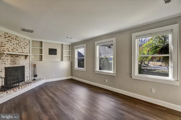 a view of an empty room with a window and fireplace