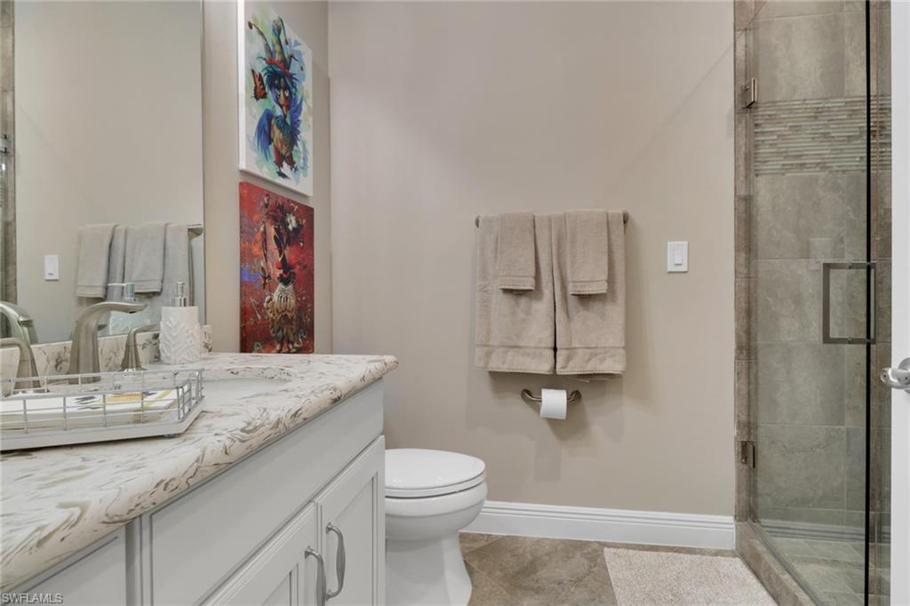 21450 Strada Nuova Circle, Unit A301 Estero, FL 33928 - Photo 20 of 40 a bathroom with a granite countertop sink mirror vanity and toilet