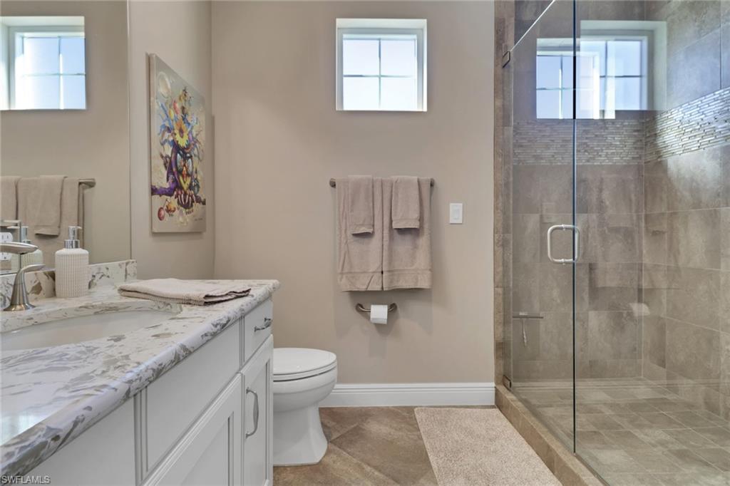 21450 Strada Nuova Circle, Unit A301 Estero, FL 33928 - Photo 21 of 40 a bathroom with a granite countertop sink a toilet and shower