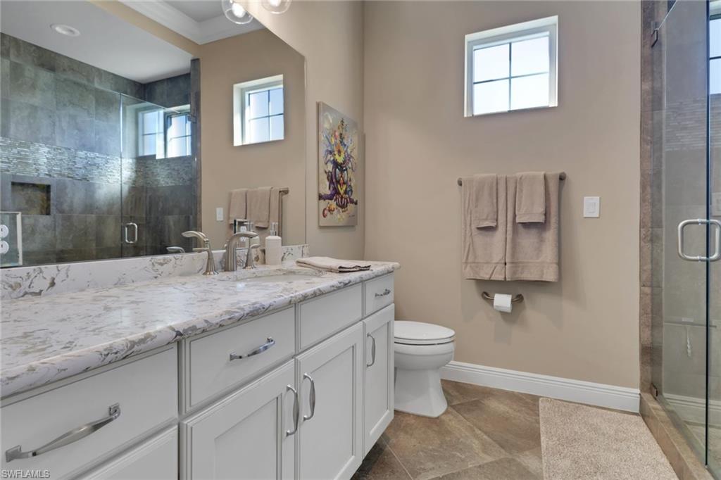 21450 Strada Nuova Circle, Unit A301 Estero, FL 33928 - Photo 22 of 40 a bathroom with a granite countertop sink a toilet and a mirror