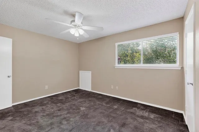 an empty room with a window and a fan