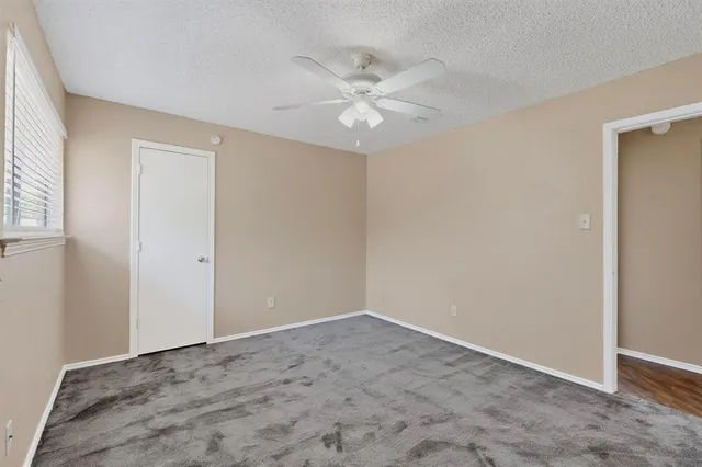 an empty room with a ceiling fan and a window