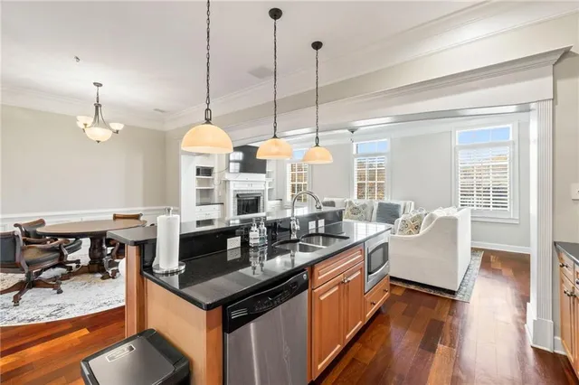 a kitchen with stainless steel appliances granite countertop a refrigerator oven a sink dishwasher and white cabinets with wooden floor