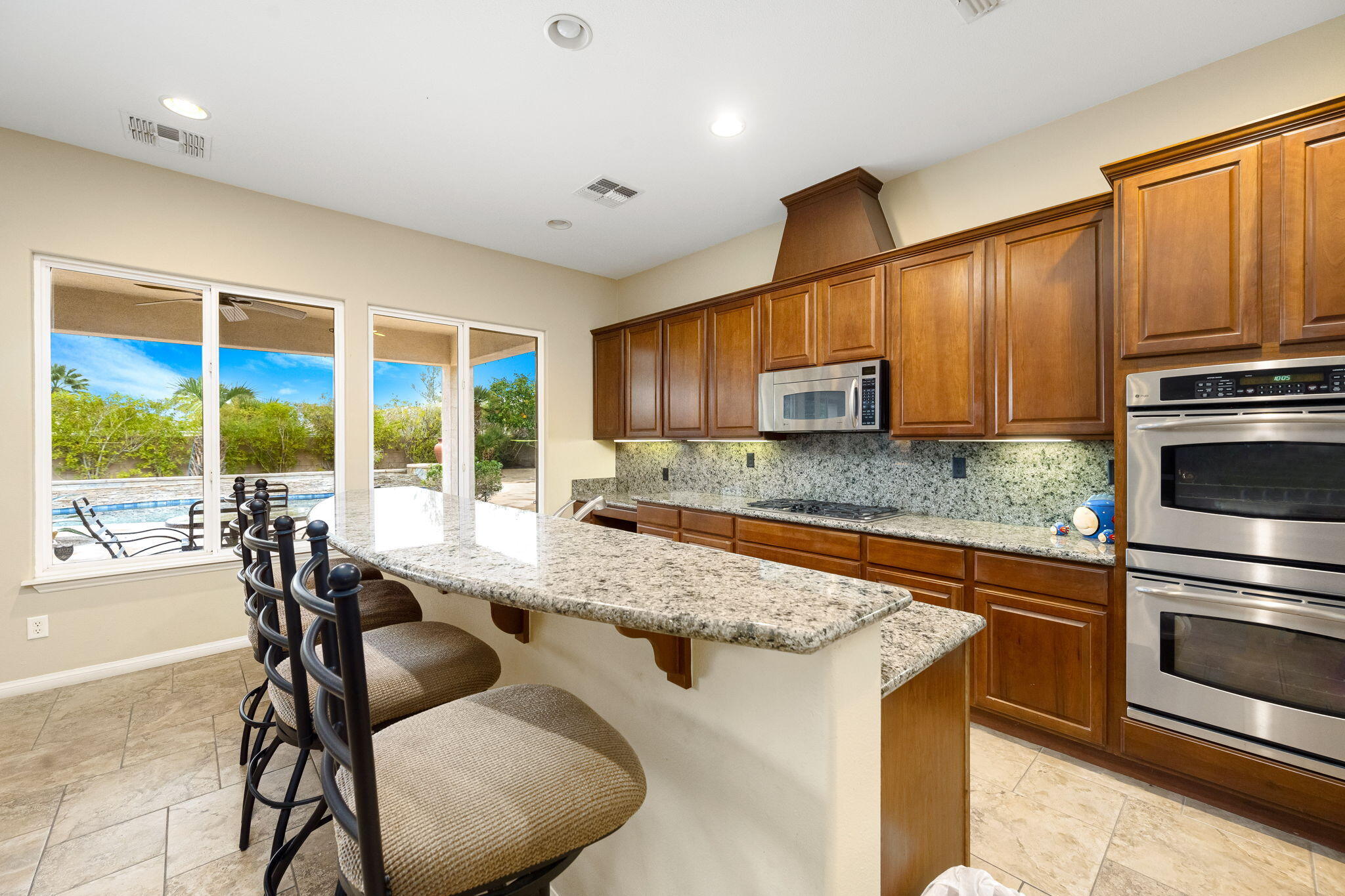 80262 Amazon Indio, CA 92201 - Photo 26 of 45 a kitchen with stainless steel appliances granite countertop a stove top oven a sink dishwasher a dining table and chairs with wooden floor