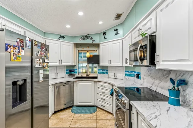 a kitchen with stainless steel appliances granite countertop a sink a stove a microwave a refrigerator and cabinets