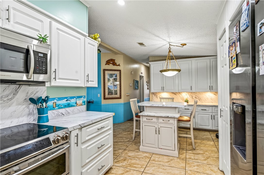 717 Wedelia Drive Sebastian, FL 32976 - Photo 9 of 24 a kitchen with kitchen island granite countertop a stove top oven microwave and cabinets