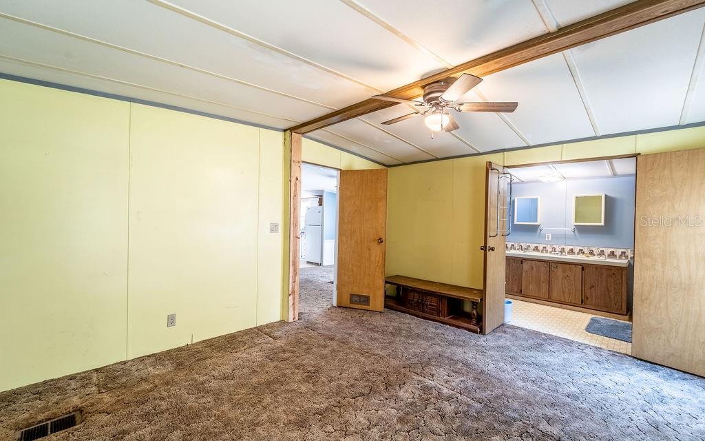 24031 Armadillo Road Astor, FL 32102 - Photo 21 of 43 a spacious bedroom with a bed and a chandelier