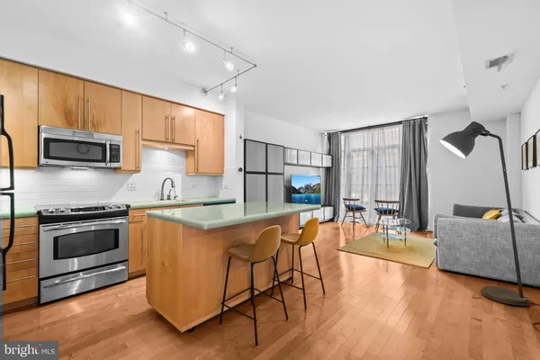 a kitchen with stainless steel appliances granite countertop a stove top oven a sink dishwasher a dining table and chairs with wooden floor