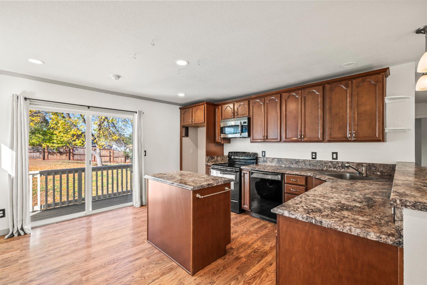4818 Fall Street El Dorado, CA 95623 - Photo 9 of 31 a kitchen with stainless steel appliances granite countertop a stove a sink dishwasher and a microwave oven with wooden floor