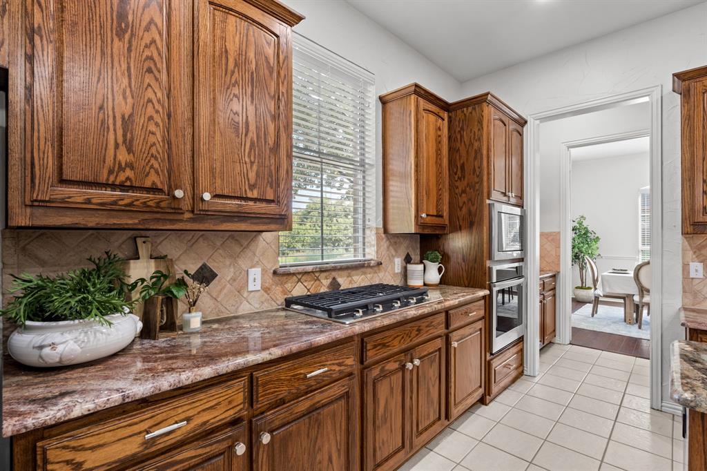 4821 Ravendale Drive Richardson, TX 75082 - Photo 17 of 40 a kitchen with stainless steel appliances granite countertop a sink a stove and a wooden cabinets