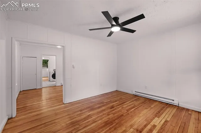 a view of empty room with wooden floor and ceiling fan