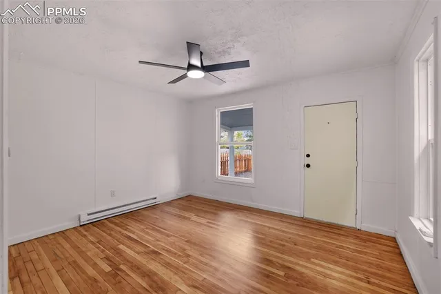 a view of empty room with wooden floor and fan