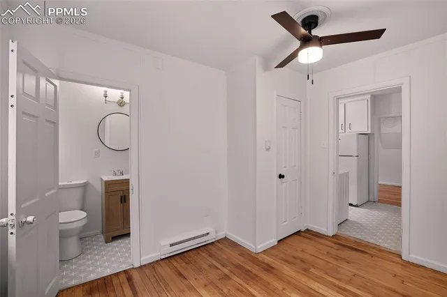 a view of a bathroom with a hardwood floor and a ceiling fan