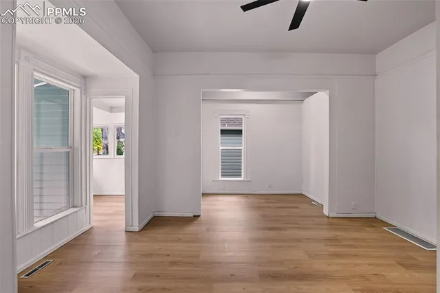 an empty room with wooden floor and windows