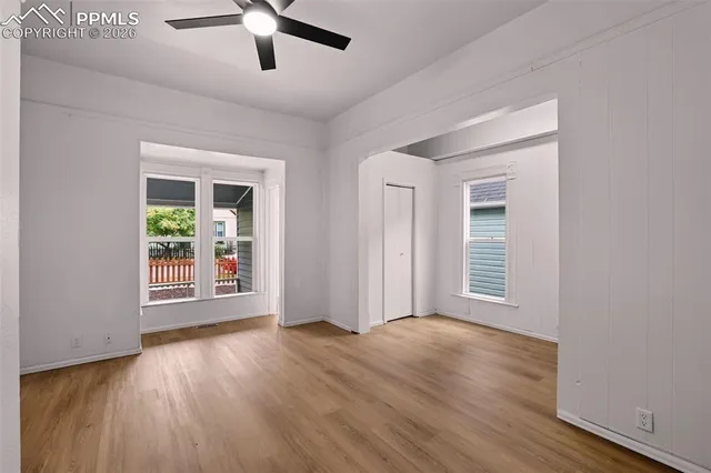 a view of an empty room with wooden floor and a window