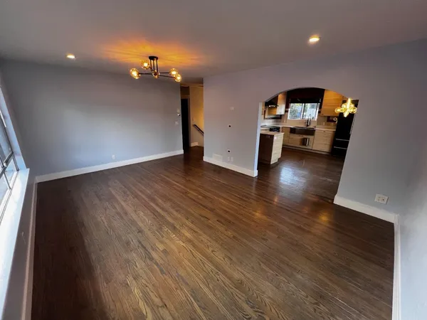 a kitchen with stainless steel appliances kitchen island granite countertop a stove a refrigerator a sink a dining table and chairs with wooden floor
