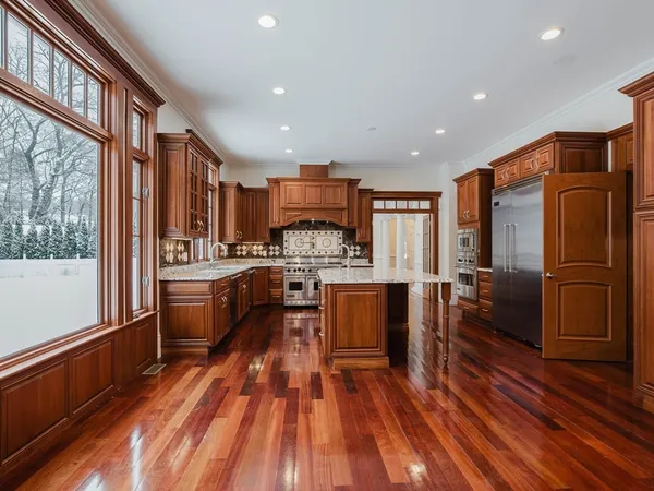 a kitchen with stainless steel appliances granite countertop a refrigerator a sink dishwasher a stove and white countertops with wooden floor