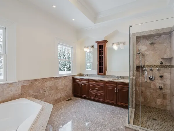 a spacious bathroom with a tub sink shower and mirror