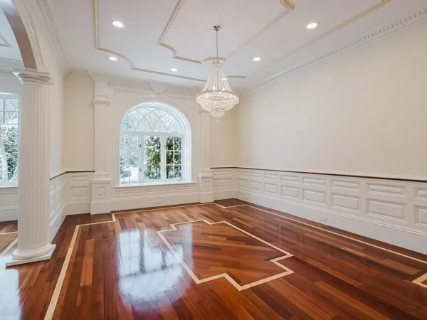a view of an empty room with wooden floor windows and a chandelier
