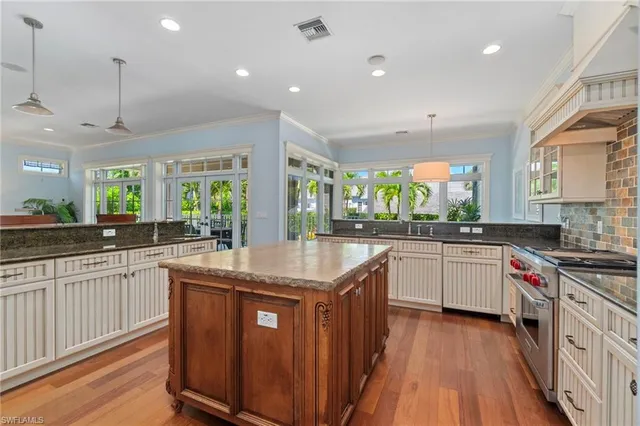 a kitchen with stainless steel appliances granite countertop hardwood floor sink stove and wooden cabinets